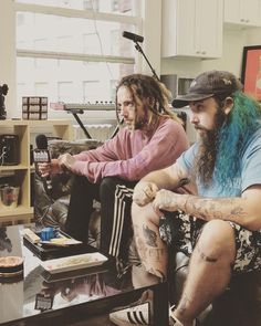 two men with long hair sitting on a couch