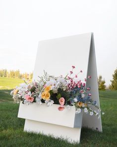 an easel with flowers in it on the grass