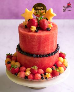 a watermelon cake with fruit on top and happy birthday sign in the middle