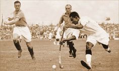 two men playing field hockey in front of an audience