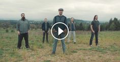 a group of people standing on top of a grass covered field next to each other