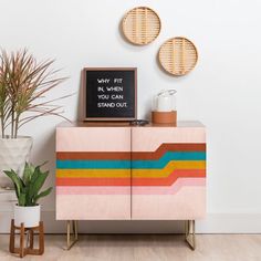 a colorful cabinet next to a potted plant and a chalkboard with the words why fit in when you can stand out