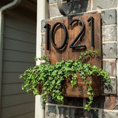 a house number sign on the side of a brick building with ivy growing in it