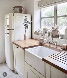 a white refrigerator freezer sitting next to a sink in a kitchen under a window