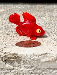 a red fish figurine sitting on top of a stone slab