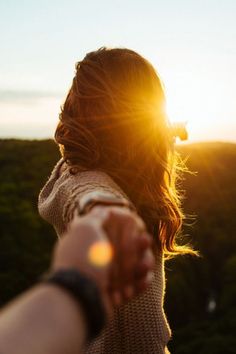 a woman holding her hand out to the sun