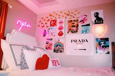 a bedroom with pink lighting and pictures on the wall above the bed, along with pillows