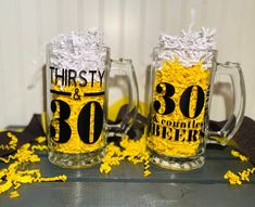 two beer mugs decorated with yellow confetti and black lettering that say thirty and 30