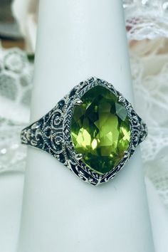 Natural Green Peridot Ring Iris Design#201 Custom Made This is a stunning Art Deco vintage reproduction ring in sterling silver filigree with a 3.12 carat Natural green peridot gemstone. The brilliant natural gem is 13mm in long by 9mm wide. The ring is 17mm North-South on the finger. The inside of the band is marked 925 for solid sterling silver. This is a lovely reproduction of a vintage antique filigree ring. There is beautiful craftsmanship evidenced in the silver filigree setting. See the f Green Jewelry With Round Cut Accent Stones, Green Sterling Silver Gemstones With Accent Stones, Green Oval Filigree Ring, Green Wedding Gemstones With Accent Stones, Green Oval Filigree Ring With Gemstone, Green Gemstone Heirloom Jewelry, Heirloom Green Jewelry With Accent Stones, Heirloom Style Green Jewelry With Accent Stones, Green Heirloom Jewelry With Accent Stones