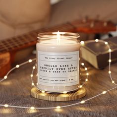 a lit candle sitting on top of a table next to a guitar and some string lights