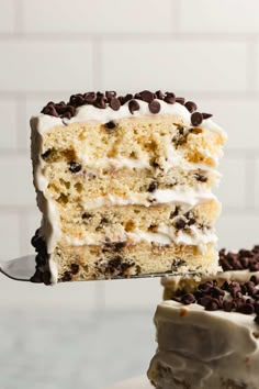 a slice of cake with white frosting and chocolate chips is being held by a fork