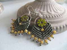 a pair of beaded earrings with yellow flowers on them sitting next to a seashell