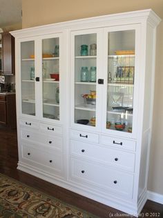 a white china cabinet with glass doors and drawers