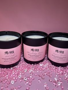 three candles sitting next to each other on a pink surface with sequins around them