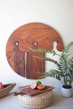 a wooden cutting board sitting on top of a table next to a potted plant