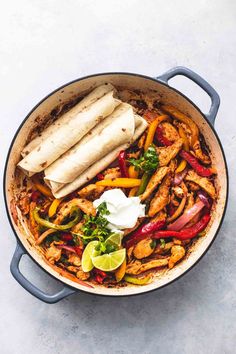 chicken fajita in a skillet with tortillas and sour cream