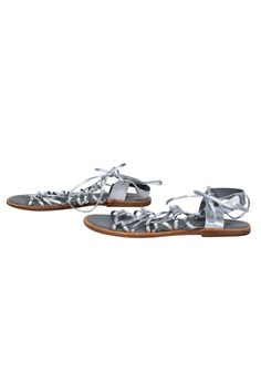 Go gladiator glam with these shiny sandals from Vince! Created with a flashy silver metallic design, these strappy beauties are perfect for bringing some glitz to your next big music music festival. Show up to the stage with some Coachella couture vibes when you pair these statement shoes with a flowy sundress and wide brim hat. Size 8.5 Leather upper w/ strappy design Lace-up closure at ankle Round toe Rubber sole and wooden footbed w/ some wear Length 10.75" Glamorous Silver Sandals For Summer, Silver Strappy Sandals For Party, Spring Silver Strappy Sandals, Silver Strappy Sandals For Spring, Silver Summer Party Sandals, Silver Sandals For Summer Party, Metallic Sandals For Summer Beach, Metallic Sandals For Beach In Summer, Metallic Silver Open Toe Sandals For Summer