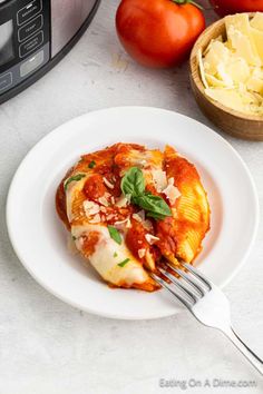 a white plate topped with lasagna covered in sauce next to an instant pressure cooker