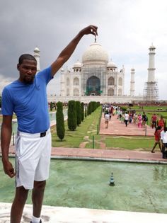 a man standing in front of a large white building with a fountain and people walking around it