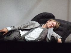 a woman laying on top of a black chair