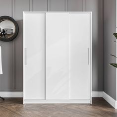 a white closet with two doors and a mirror on the wall next to a chair