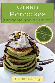 green pancakes with whipped cream and chocolate drizzled on top, sitting on a white plate