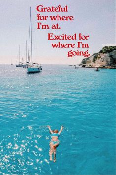 a woman swimming in the ocean with a sailboat behind her and an advertisement that reads grateful for where i'm at