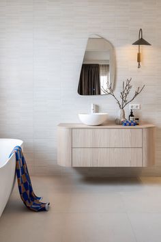 a bathroom with a sink, mirror and bathtub next to a large white tub