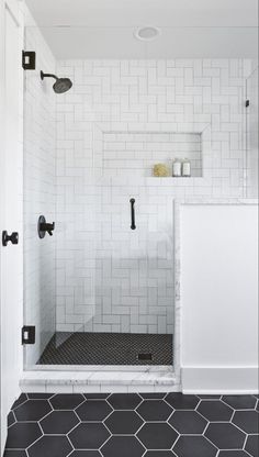 a bathroom with black and white tile flooring, shower head, and shelves on the wall