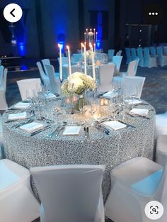 the table is set with white linens and silver sequined tablescloths