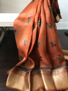 This is a beautiful printed organza saree in earthy brown with beautiful prints all over the body. Blouse has a satin feel with a stone washed look. Saree has floral and fruit prints. Upper narrow border has floral motif and the wider lower border is heavy and grand. Zari borders gives a good contrast to brown body. Last picture shows the blouse piece  * Colour may vary slightly due to lighting  * Handloom products may have slight irregularities * All sales are final * No falls or pico done * Maintenance: Dry clean only Traditional Chanderi Wear With Floral Print, Transitional Floral Print Dupatta With Traditional Drape, Transitional Floral Print Dupatta, Transitional Season Floral Print Dupatta, Transitional Floral Print Traditional Dupatta, Festive Floral Print Saree For Transitional Season, Traditional Chanderi Saree With Floral Print, Chanderi Saree With Floral Print In Traditional Drape, Traditional Floral Print Dupatta For Transitional Season