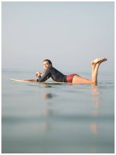 a woman laying on a surfboard in the ocean with her legs spread out,