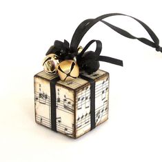 an ornament with musical notes and bells on it's side, tied to a black ribbon