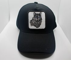 a black hat with a white wolf embroidered on the front and blue eyes, sitting on a white surface