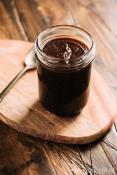 a jar of chocolate spread on a wooden cutting board with a spoon