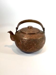 an antique teapot with a wooden handle on a white background