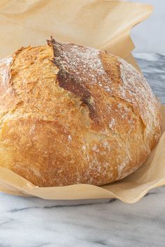 a loaf of bread sitting on top of a table next to a paper wrapper