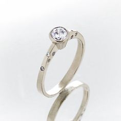 an engagement ring with a diamond in the center and two diamonds on each side, set against a plain white background