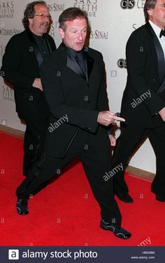 two men in tuxedos are dancing on the red carpet