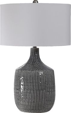 a gray and white striped lamp with a white shade on the bottom, sitting on a table