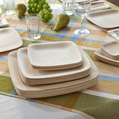 a table topped with plates and glasses filled with green grapes on top of a checkered table cloth