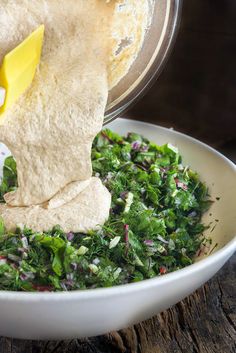 someone is mixing ingredients in a bowl with tortilla wrappers on the side