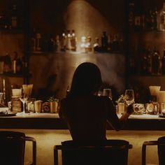 a woman sitting at a bar with wine glasses