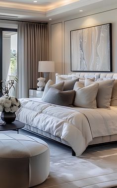 a large white bed sitting in a bedroom next to a tall window covered in curtains