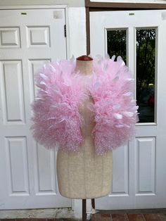 a mannequin with pink and white feathers on it's head in front of a door