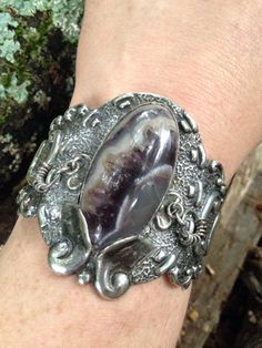 "A fine early Mexican sterling silver cuff bracelet with lace agate. This heavy sterling cuff features a complex lace agate cabochon (23mm x 45mm) with colors in the range of purple, grey, and white. The stone almost looks to have interior crystals and looks more purple in sunlight. Next to the stone on either side are two little dangles made from rings. These shake and move when you walk and make a little click click rattle. Bracelet is easy on and off and secure for wearing. Hand etched to say Silver Agate Bangle Cuff Bracelet, Unique Silver Bracelet With Cabochon, Silver Artisan Agate Bracelets, Artisan Silver Agate Bracelets, Unique Handmade Agate Cuff Bracelet, Handmade Unique Agate Cuff Bracelet, Unique Silver Agate Cuff Bracelet, Handmade Agate Cuff Bracelet Unique Style, Silver Agate Gemstone Cuff Bracelet