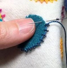 the needle is being used to sew on something blue and yellow with other crochet stitches