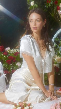 a woman sitting on the ground in front of flowers