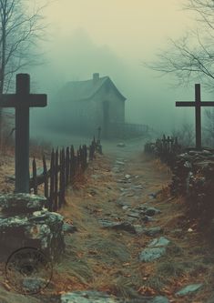 two crosses on the side of a dirt road in front of a foggy church