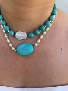 a woman wearing a blue and white beaded necklace with two large stones on it